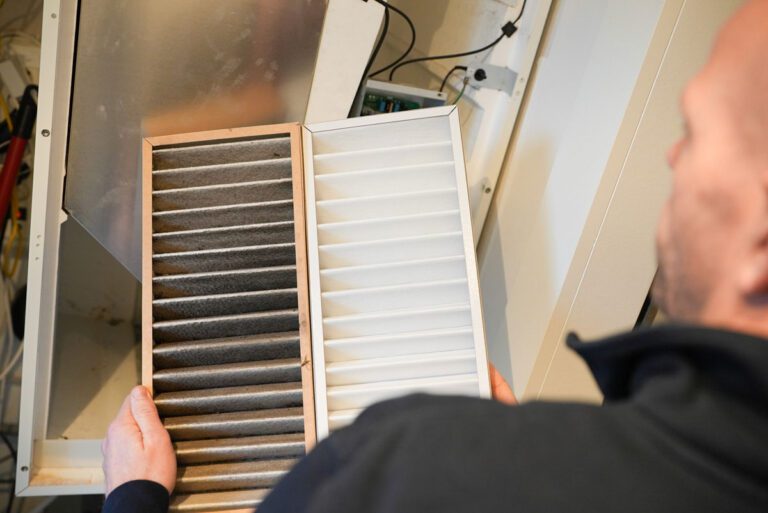 En medarbejder fra Jysk Ventilationsservice er ved at skifte filtre i ventilationsanlæg. Han holder et rent og beskidt filter op ved siden af hinanden