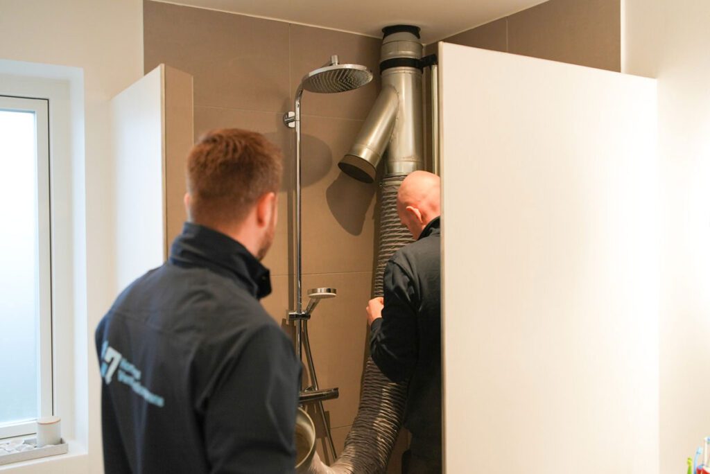 To medarbejdere fra Jysk Ventilationsservice i gang med at rense ventilationsrør i et badeværelse