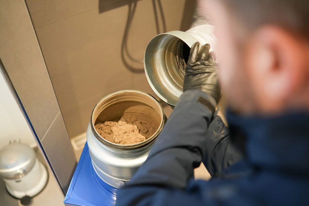 Foto af ventilationsrens taget over skulderen på medarbejder i gang med at suge støv ud af ventilationskanalerne