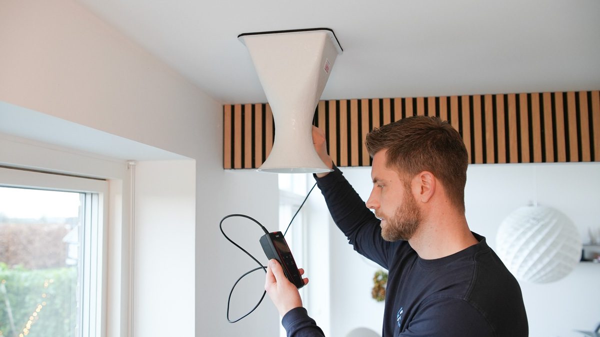 Medarbejder fra Jysk Ventilationsservice m&aring;ler effekten i en ventilationskanal