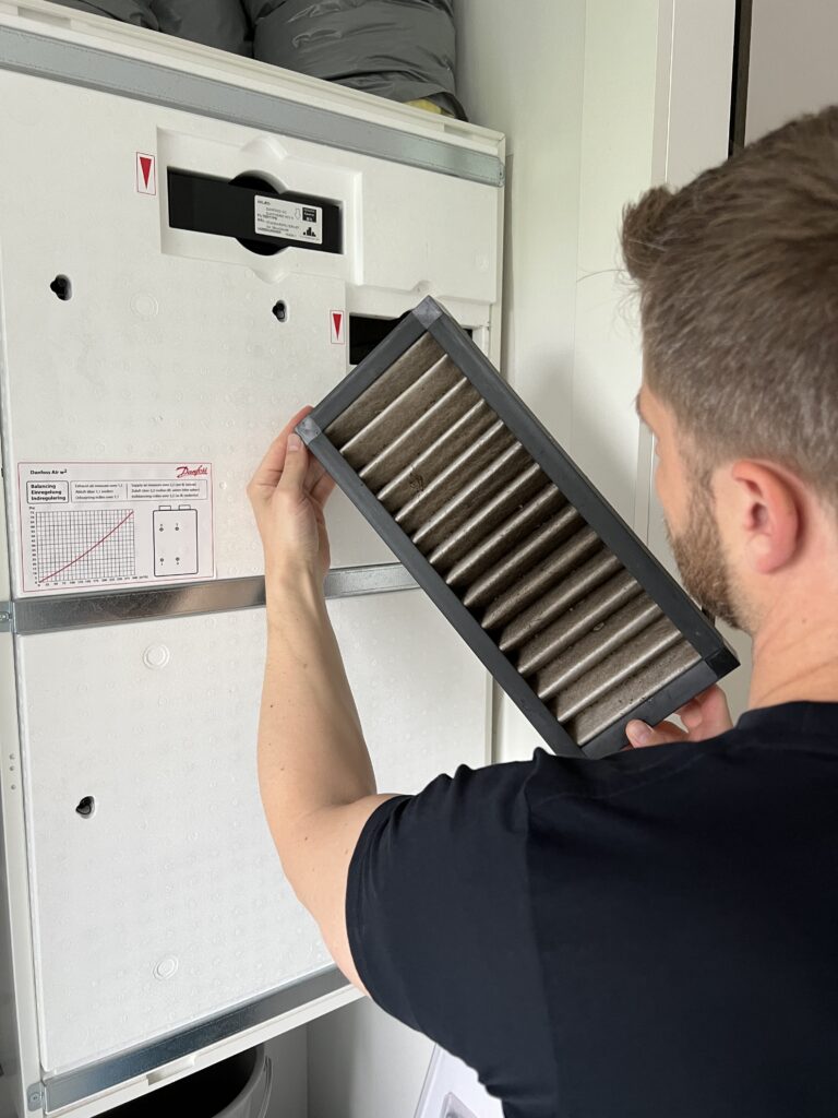 En professionel ventilationsservice tekniker i gang med udskiftning af filter i dit ventilationsanlæg.